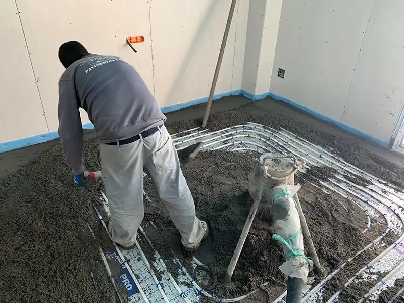 Operario haciendo el solado de mortero sobre suelo radiante.