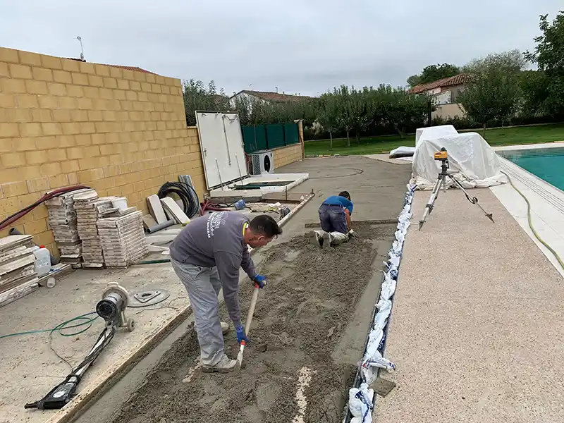 Operarios echando la solera alrededor de una piscina.
